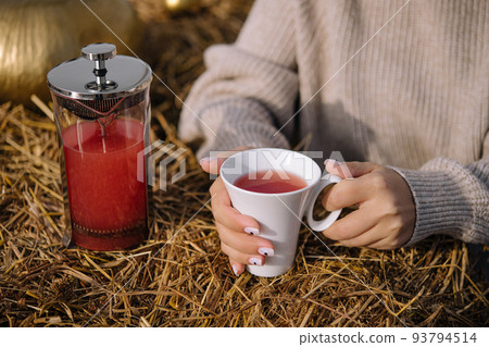 A woman holds a cup of tea close up 93794514