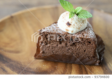 Cut chocolate cake decorated with fresh cream and mint 93794600