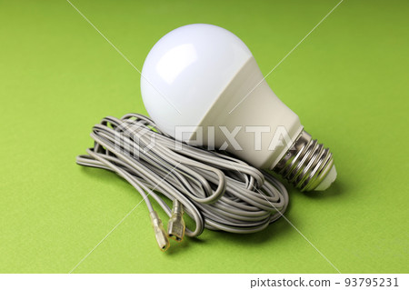Energy saving bulb and wire on green background Energy saving bulb and wire on green background 93795231