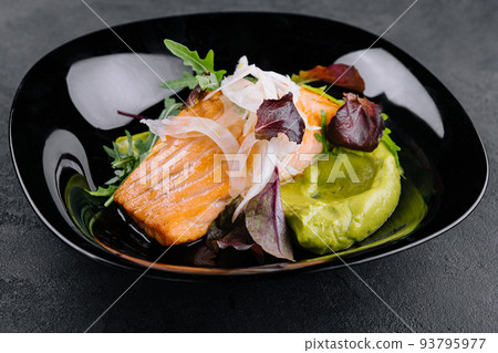 Close-up of grilled salmon fillet with green arugula sprouts with mashed avocado on a plate. Close-up of grilled salmon fillet with green arugula sprouts with mashed avocado on a plate. 93795977