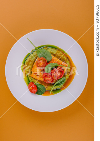 salmon steak with mashed avocado, decorated with basil leaves and cherry tomatoes salmon steak with mashed avocado, decorated with basil leaves and cherry tomatoes 93796015