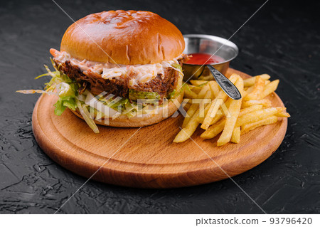 Delicious hamburger with cheese sauce and french fries on wooden table Delicious hamburger with cheese sauce and french fries on wooden table 93796420