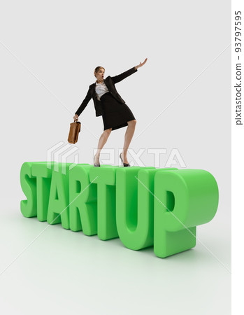 Motivated young woman walking on big letters of startup. Maintaining successful company Motivated young woman walking on big letters of startup. Maintaining successful company 93797595