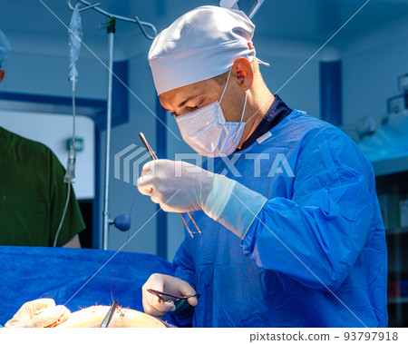 A male surgeon stitches up the patient's skin. A male surgeon stitches up the patient's skin. 93797918