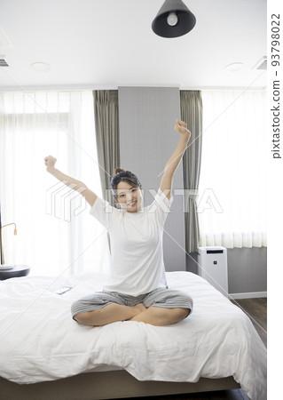 Young woman stretching in her bedroom in the morning Young woman stretching in her bedroom in the morning 93798022
