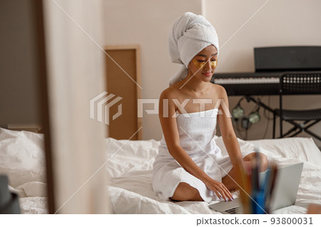 Asian young woman using laptop after shower at home Asian young woman using laptop after shower at home 93800031