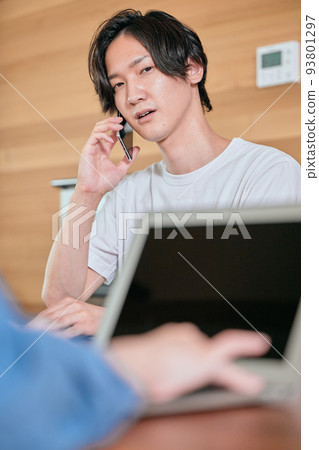 A young man calling on his smartphone during telework A young man calling on his smartphone during telework 93801297