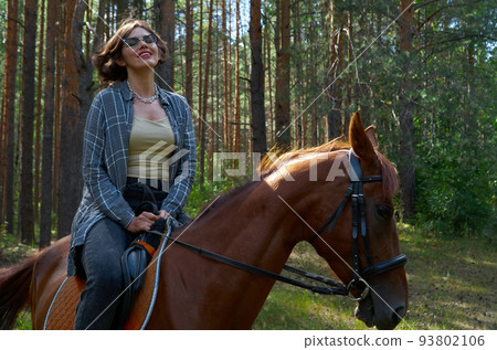 Woman in casual clothes rides a horse in hot summer day 93802106