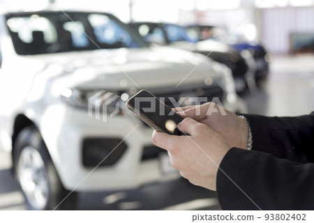 Salesman using mobile smart phone. Dealer showroom 93802402