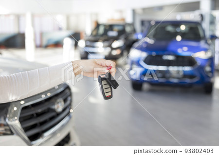 Dealer woman holding keys to a new car. Dealer woman holding keys to a new car. 93802403
