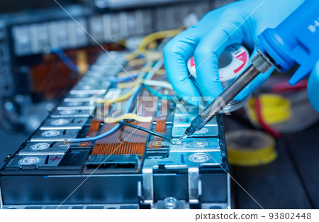 Technician use soldering iron to solder metal and wire of lithium-ion rechargeable battery. Repair module of Li-ion battery. Engineer hand holds soldering iron and tin-lead to solder electronic board. 93802448
