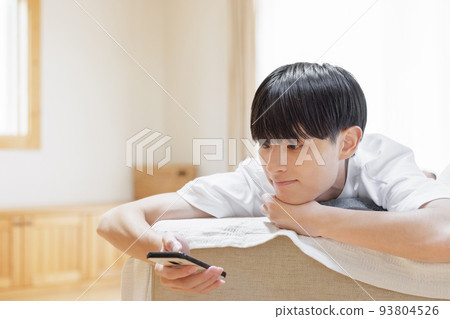 A man looking at a smartphone while lazing on the sofa 93804526