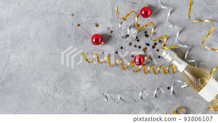 New Year background with golden champagne bottle, confetti stars and party serpentine top view on grey table. New Year background with golden champagne bottle, confetti stars and party serpentine top view on grey table. 93806107
