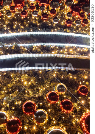 Golden and red christmas ornament balls and garland with lights on Christmas tree background. Golden and red christmas ornament balls and garland with lights on Christmas tree background. 93806150