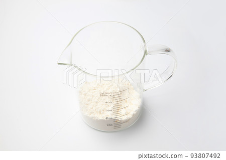 Glass measuring cup with flour White background 93807492