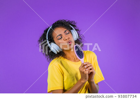 African woman singing and dancing with hair brush or comb instead microphone at purple studio 93807734