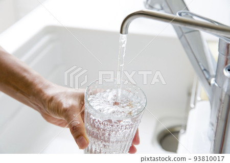 一位家庭主婦的手,她用淨水器的水裝滿玻璃杯 一位家庭主婦的手,她用淨水器的水裝滿玻璃杯 93810017