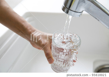 Housewife's hand filling the glass with water in the kitchen Housewife's hand filling the glass with water in the kitchen 93810021