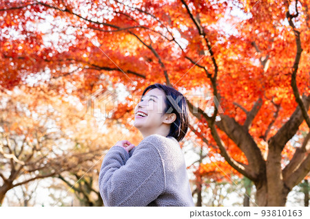 Young woman enjoying autumn leaves hunting 93810163