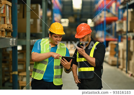 Warehouse managers and worker checking newly arrived goods on digital tablet while standing near tall shelves in large warehouse Warehouse managers and worker checking newly arrived goods on digital tablet while standing near tall shelves in large warehouse 93816183