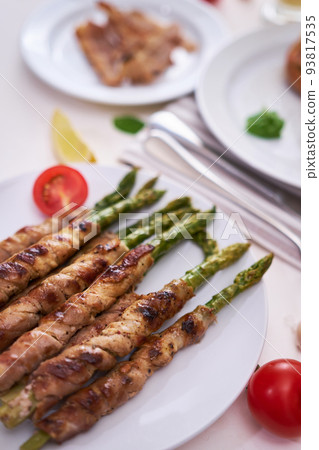 Tasty breakfast - Asparagus wrapped with bacon and spices on a plate Tasty breakfast - Asparagus wrapped with bacon and spices on a plate 93817535