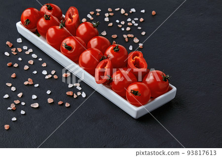 An elongated plate of tomatoes, paprika and coarse pink Tibetan salt on a black concrete table An elongated plate of tomatoes, paprika and coarse pink Tibetan salt on a black concrete table 93817613
