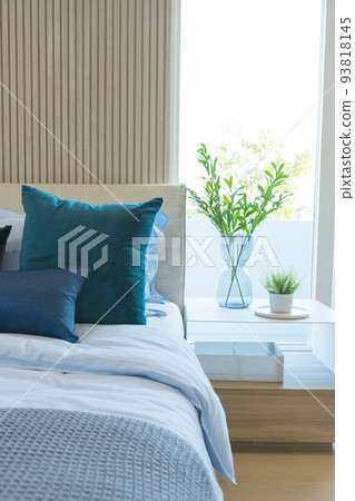 Yellow and green pillow on bed with table lamp on bedside table in modern interior bedroom. Yellow and green pillow on bed with table lamp on bedside table in modern interior bedroom. 93818145