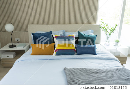 Yellow and green pillow on bed with table lamp on bedside table in modern interior bedroom. Yellow and green pillow on bed with table lamp on bedside table in modern interior bedroom. 93818153