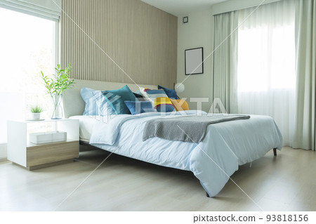 Yellow and green pillow on bed with table lamp on bedside table in modern interior bedroom. 93818156