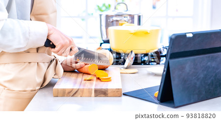 Image cut of a housewife who cooks while watching a video of a tablet computer in the kitchen 93818820