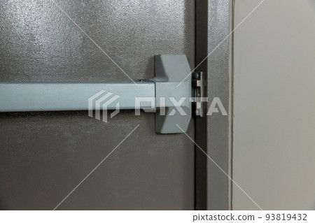 Emergency fire exit door. Closed up latch and rusty door handle of emergency exit. Emergency fire exit door. Closed up latch and rusty door handle of emergency exit. 93819432