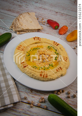 Homemade hummus with tahini plate with olive oil and paprika and pita isolated on brown background 93821074