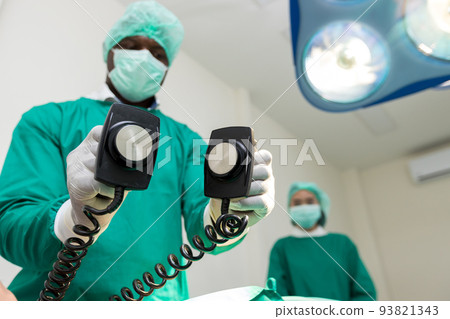 The doctor is giving a defibrillators to save the patient's life in the hospital. 93821343