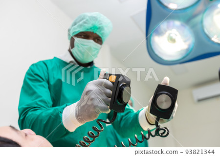 The doctor is giving a defibrillators to save the patient's life in the hospital. The doctor is giving a defibrillators to save the patient's life in the hospital. 93821344
