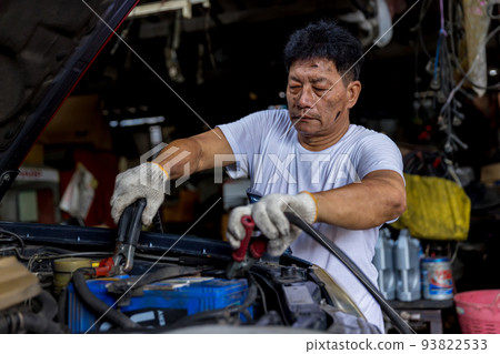 Man charging battery car with electricity cables. Man charging battery car with electricity cables. 93822533
