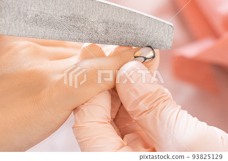 Manicure salon woman receiving a manicure by a beautician with nail file. Woman getting nail Manicure salon woman receiving a manicure by a beautician with nail file. Woman getting nail 93825129