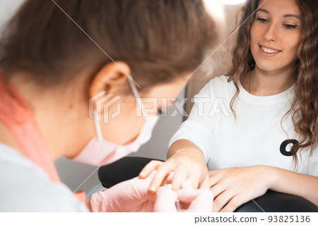 Manicure salon woman receiving a manicure by a beautician with nail file. Woman getting nail 93825136