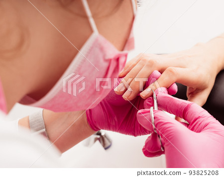 Manicure salon master removes cuticles with nail scissors. Woman getting nail manicure. Professional 93825208