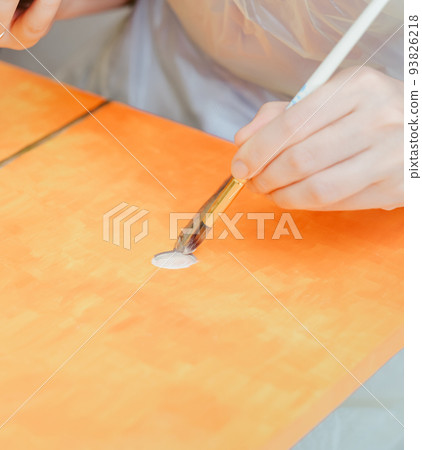 art, creativity and inspiration concept, female hand with paintbrush painting at home or studio on orange canvas. 93826218