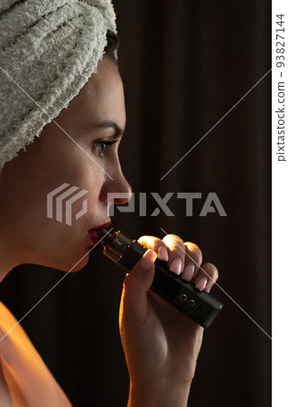 A girl is blowing smoke from a vape, a portrait of a girl with red lips who smokes. 93827144