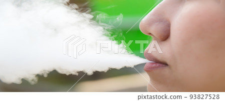 smoking a cigarette smoke. woman smoking an e-cigarette. smoking a cigarette smoke. woman smoking an e-cigarette. 93827528