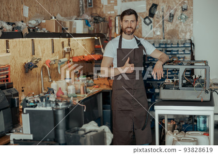 Portrait of handsome repairman with coffee machine in a workshop 93828619