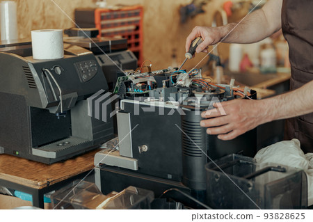 Close up of man hands repairing coffee machine in a workshop 93828625
