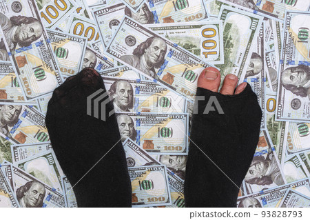 Legs in torn socks stand on a pile of money Legs in torn socks stand on a pile of money 93828793
