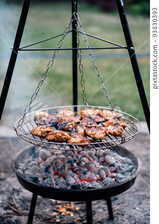 Grilled Chicken Thighs on charcoal grill outdoors. BBQ Chicken. Frilling bone-in chicken legs, thighs 93830393