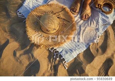 Top view of beach accessories. Straw hat, bag, flip flops on sand at beach. 93830689