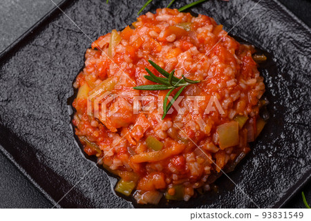Boiled rice with peppers, spices, herbs and tomato sauce on a black slate plate Boiled rice with peppers, spices, herbs and tomato sauce on a black slate plate 93831549