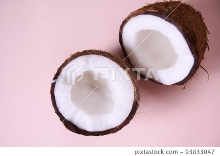 Still life. Close-up of halves of ripe organic raw vegan coconuts, shot with soft shadow isolated on pink background with copy space for promotional text. Exotic tropical palm fruits. Healthy eating Still life. Close-up of halves of ripe organic raw vegan coconuts, shot with soft shadow isolated on pink background with copy space for promotional text. Exotic tropical palm fruits. Healthy eating 93833047