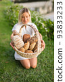Young woman in white dress sitting on the grass with basket with assorti of brown and white homemade bread. High quality photo 93833233