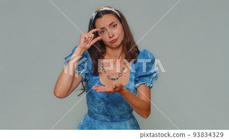 Woman showing a little bit gesture with sceptic smile, showing minimum sign, measuring small size Woman showing a little bit gesture with sceptic smile, showing minimum sign, measuring small size 93834329